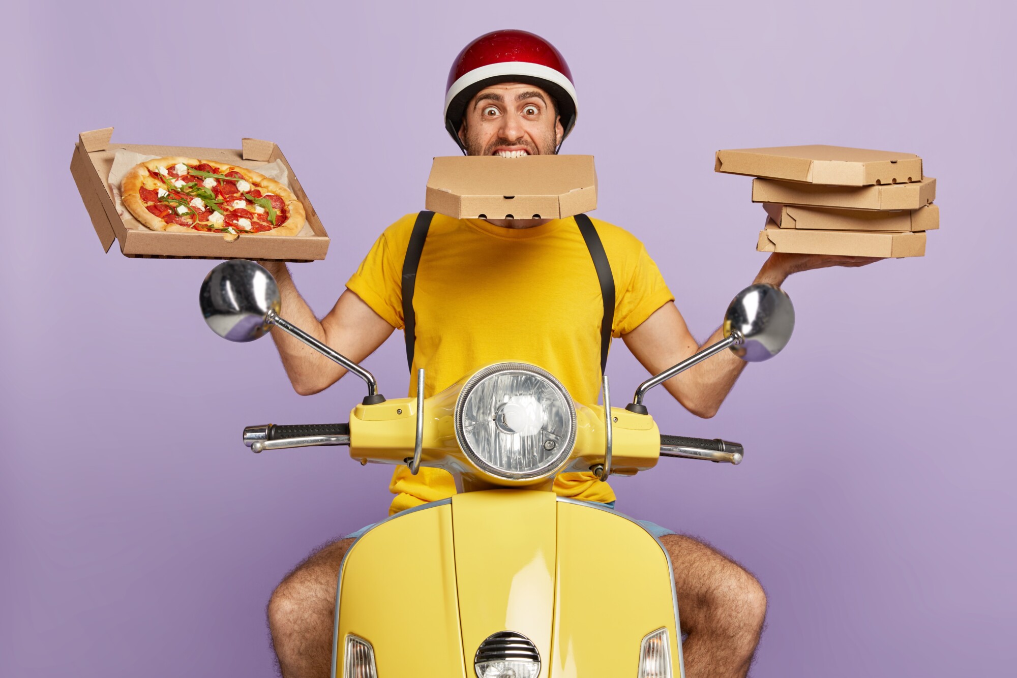 busy-deliveryman-driving-yellow-scooter-while-holding-pizza-boxes