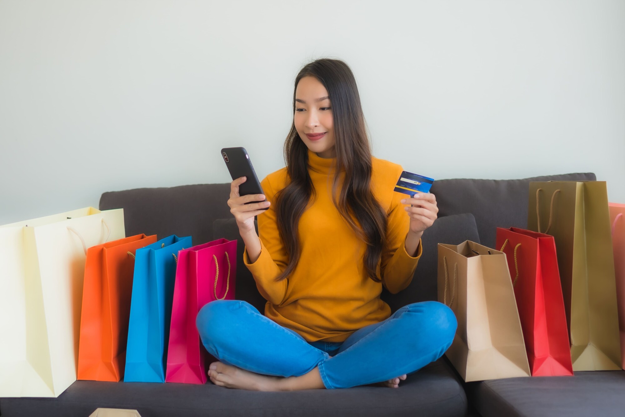 portrait-young-asian-woman-using-laptop-computer-with-smart-mobile-phone-credit-card-online-shopping (1)